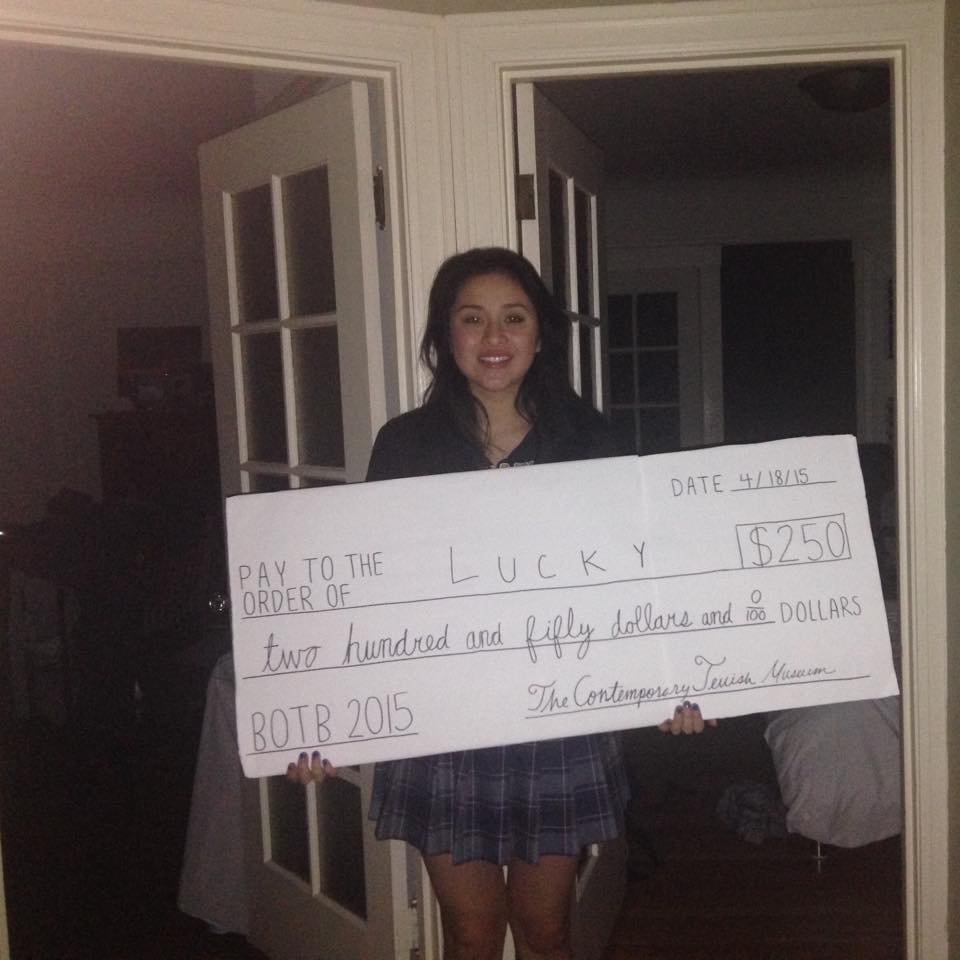 A girl holding up a large check in front of her.