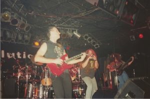A man playing guitar on stage with other people.