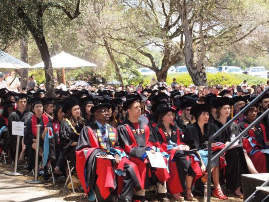 A group of people in graduation robes sitting on chairs.