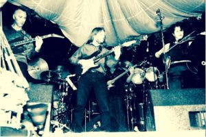A man playing guitar in front of a band.