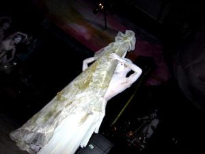 A white dress is shown on display in the dark.