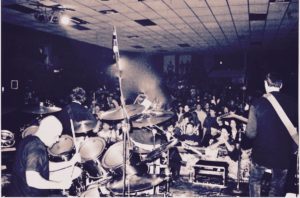 A crowd of people in a room with drums.