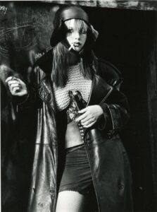 A woman in a leather coat holding a gun.