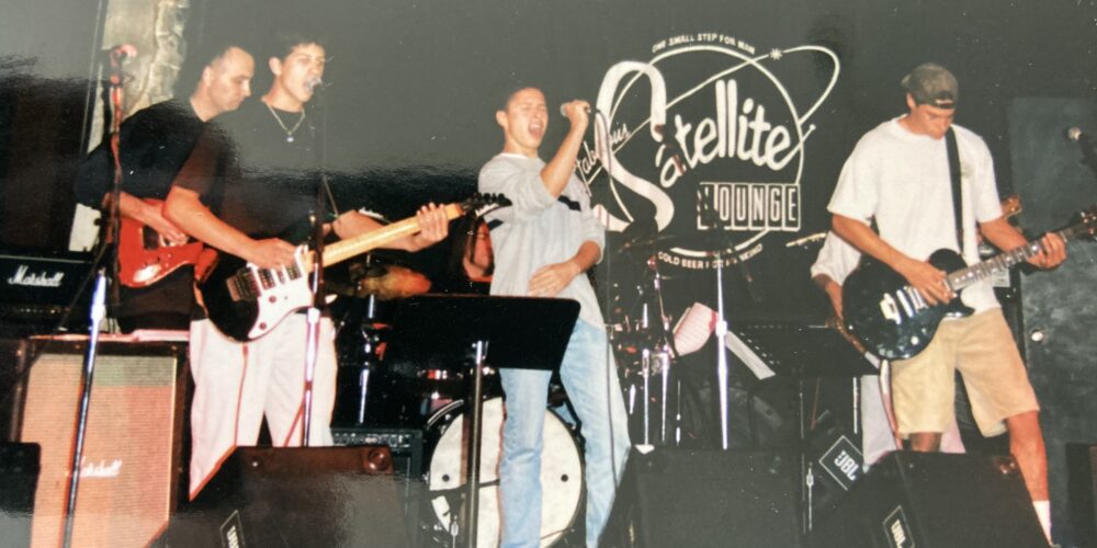A band performing on stage with the word " satellite ".